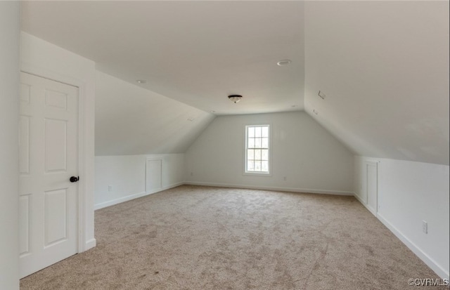 additional living space with light carpet and vaulted ceiling