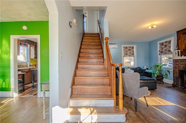 stairway featuring hardwood / wood-style floors and a fireplace