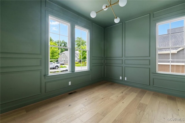 15812 W Millington Dr, Midlothian, VA 23112 - empty room featuring a decorative wall, a chandelier, plenty of natural light, and light wood finished floors