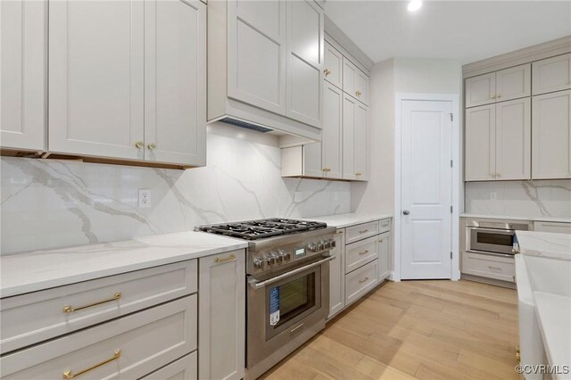 15812 W Millington Dr, Midlothian, VA 23112 - kitchen featuring high end stainless steel range oven, decorative backsplash, light wood finished floors, and light stone counters