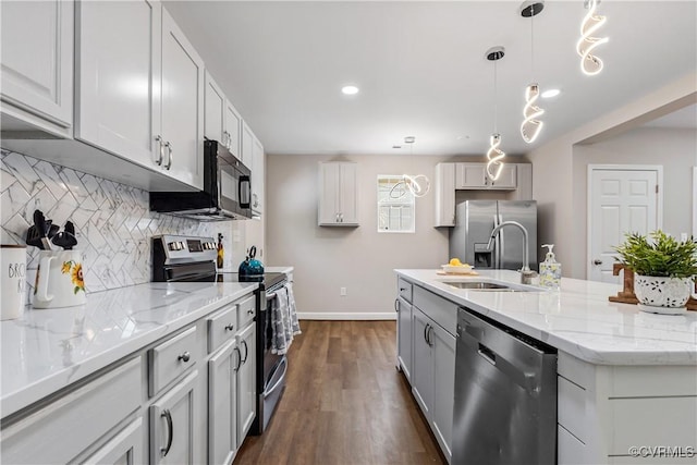 kitchen featuring pendant lighting, sink, an island with sink, appliances with stainless steel finishes, and dark hardwood / wood-style flooring