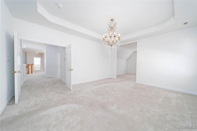 carpeted empty room featuring a chandelier and a raised ceiling