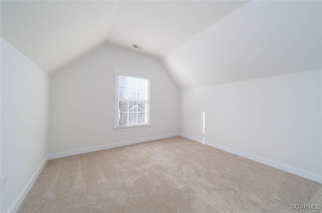 additional living space with light carpet and vaulted ceiling