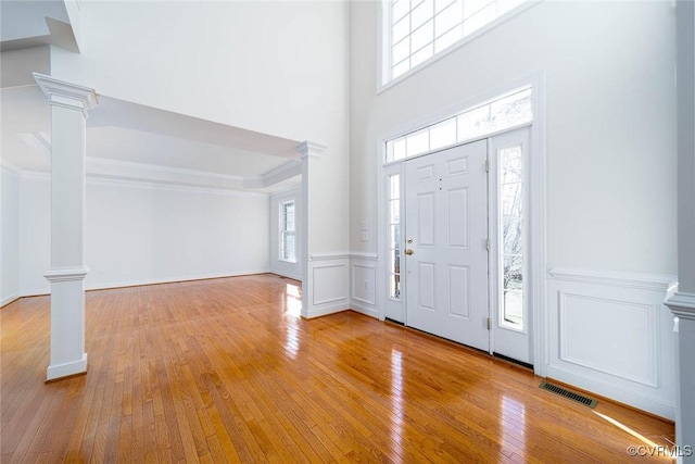 entryway featuring decorative columns, a healthy amount of sunlight, and light wood-type flooring