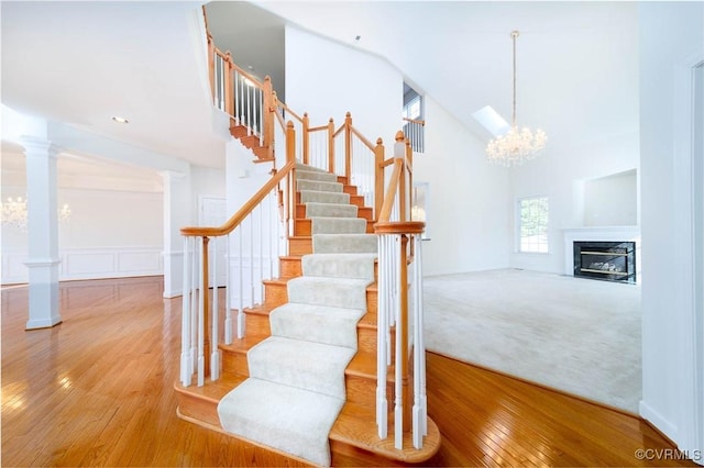 stairway featuring hardwood / wood-style flooring, a notable chandelier, and decorative columns