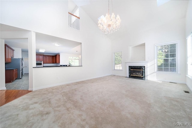 unfurnished living room featuring a wealth of natural light, a premium fireplace, light carpet, and high vaulted ceiling