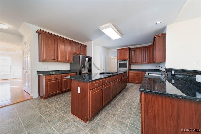 kitchen featuring dark stone countertops, a center island, sink, and stainless steel appliances