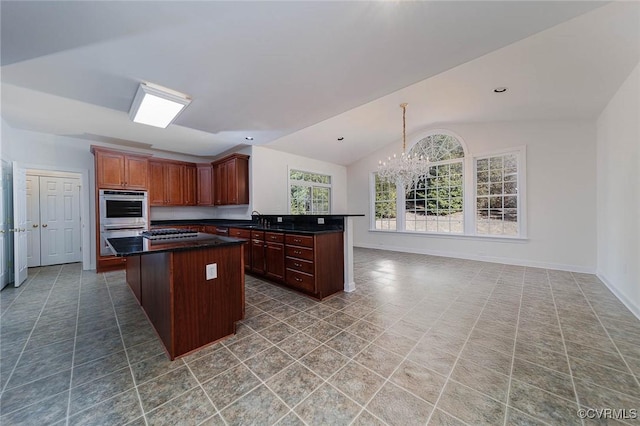 kitchen featuring an inviting chandelier, sink, vaulted ceiling, double oven, and a kitchen island