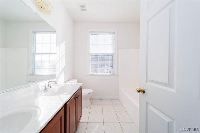 bathroom with tile patterned flooring, vanity, a healthy amount of sunlight, and toilet