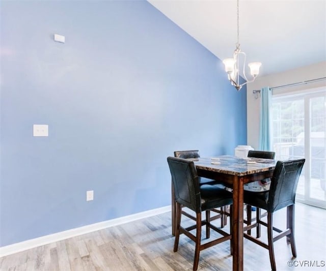 dining space featuring lofted ceiling, light hardwood / wood-style flooring, and a notable chandelier