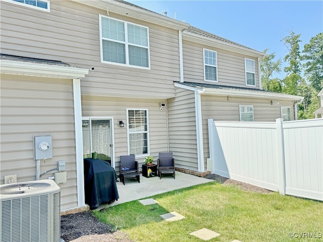 rear view of house featuring a lawn, a patio, and central AC