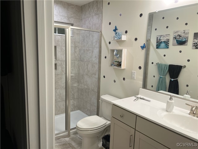 bathroom with tile patterned floors, vanity, a shower with shower door, and toilet