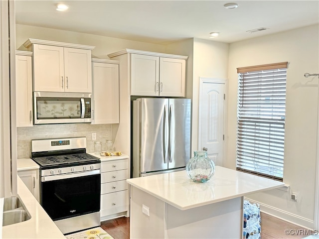 kitchen featuring white cabinets, appliances with stainless steel finishes, dark hardwood / wood-style flooring, and tasteful backsplash