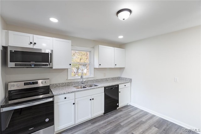 kitchen with sink, light hardwood / wood-style floors, light stone counters, white cabinetry, and stainless steel appliances