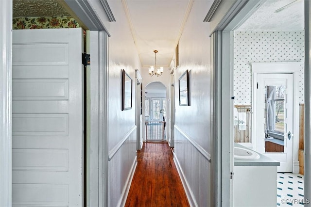 hall with crown molding, dark hardwood / wood-style floors, and an inviting chandelier