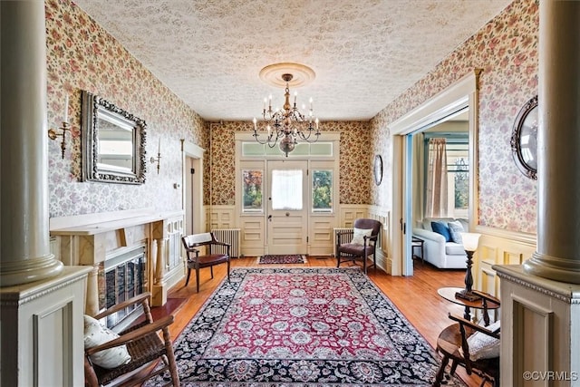 living area with radiator, hardwood / wood-style floors, plenty of natural light, and a notable chandelier