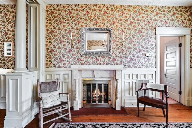 sitting room with decorative columns and dark wood-type flooring