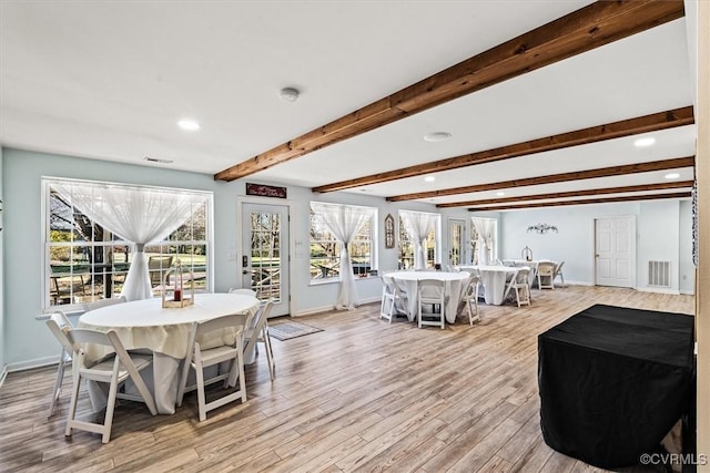 dining room with beam ceiling and light wood-type flooring