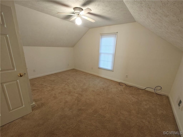 additional living space featuring ceiling fan, vaulted ceiling, light carpet, and a textured ceiling