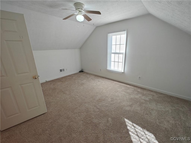 bonus room featuring ceiling fan, light colored carpet, lofted ceiling, and a textured ceiling