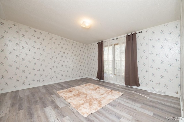 unfurnished room featuring hardwood / wood-style floors and a textured ceiling