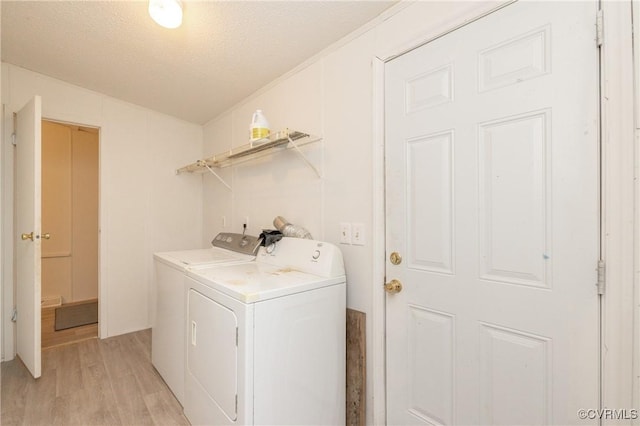 washroom featuring washing machine and dryer, a textured ceiling, and light hardwood / wood-style flooring