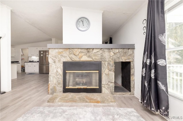 interior details featuring hardwood / wood-style flooring, stainless steel refrigerator, and a stone fireplace