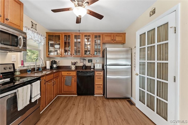 kitchen with ceiling fan, sink, light wood-type flooring, and stainless steel appliances