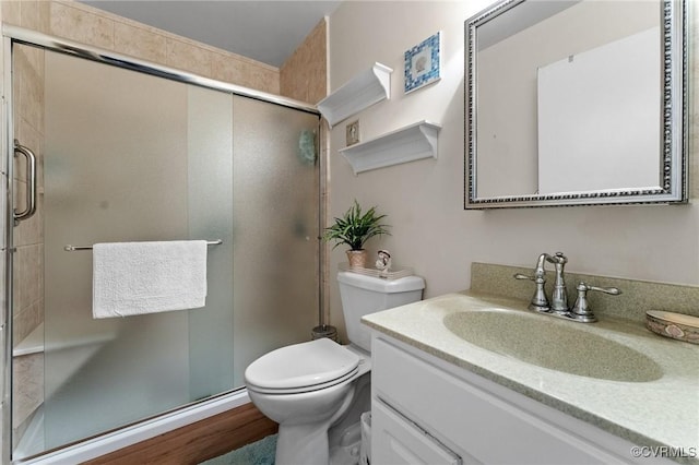 bathroom with wood-type flooring, vanity, a shower with shower door, and toilet