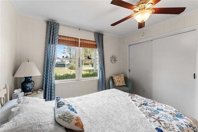 bedroom featuring wooden walls, a closet, ceiling fan, and ornamental molding