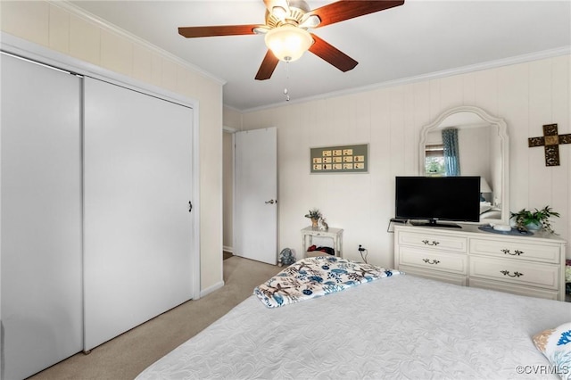 bedroom with ceiling fan, crown molding, light carpet, and a closet