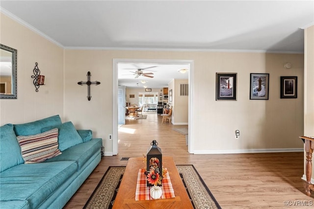 living room featuring crown molding, ceiling fan, and light wood-type flooring