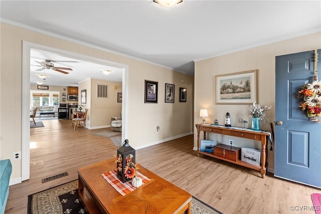 living room with ceiling fan, light wood-type flooring, and ornamental molding