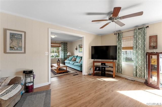 living room with ceiling fan, ornamental molding, and light wood-type flooring