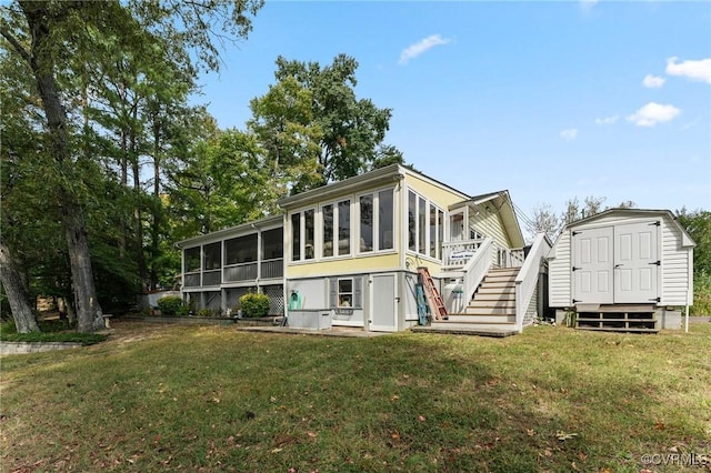 rear view of property featuring a sunroom, a storage shed, and a lawn