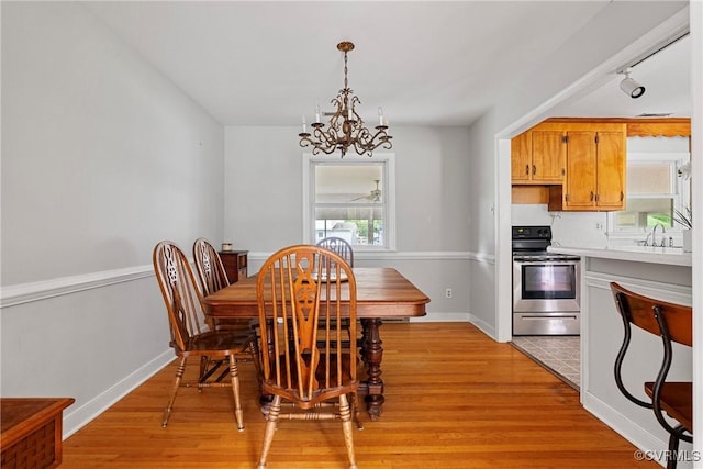 dining room with rail lighting, light hardwood / wood-style floors, sink, and a chandelier