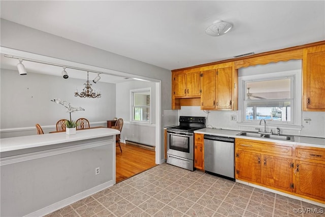 kitchen with decorative light fixtures, sink, appliances with stainless steel finishes, and a baseboard heating unit