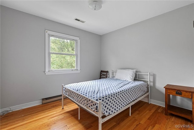 bedroom with a baseboard radiator and wood-type flooring