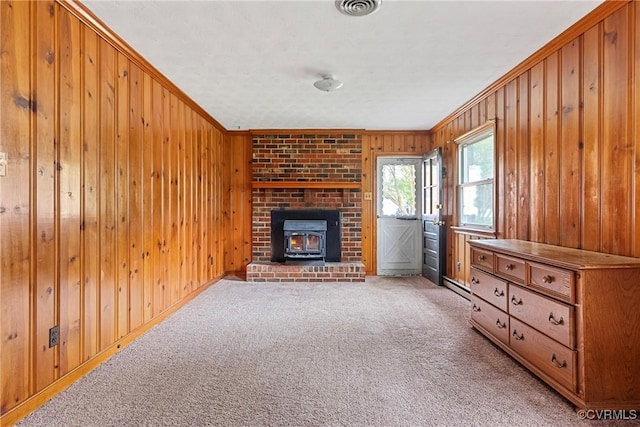 living room with light carpet, a wood stove, crown molding, and wood walls