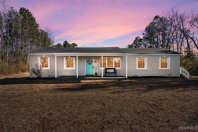 ranch-style home featuring a yard, brick siding, crawl space, and a porch