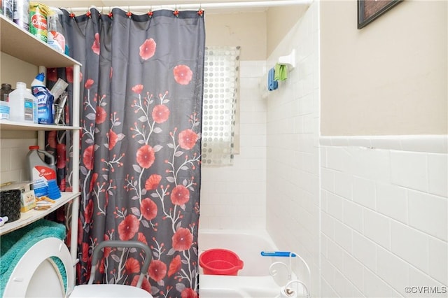 bathroom with shower / bath combo with shower curtain, tile walls, and toilet