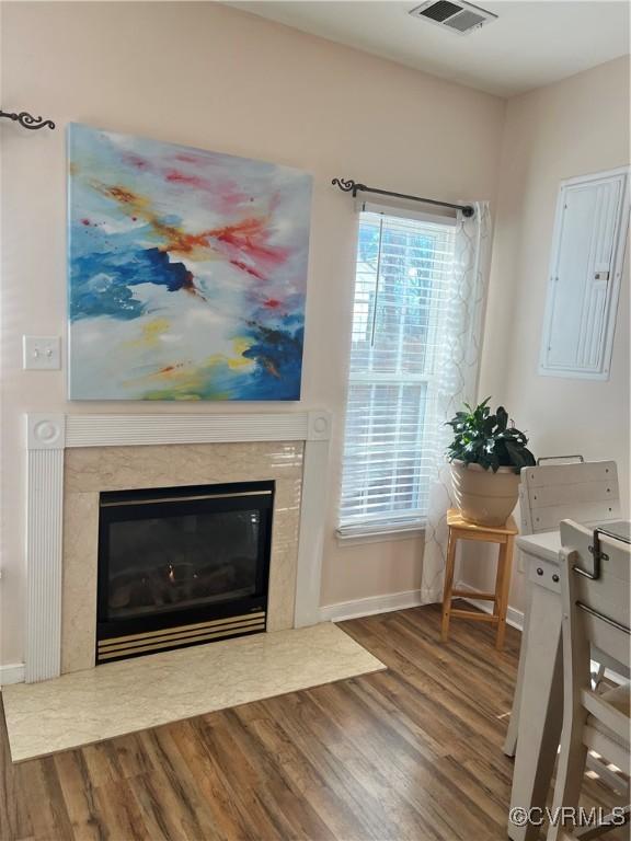 living room featuring electric panel, a high end fireplace, and wood-type flooring