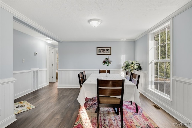 dining room featuring dark hardwood / wood-style flooring, a textured ceiling, and ornamental molding