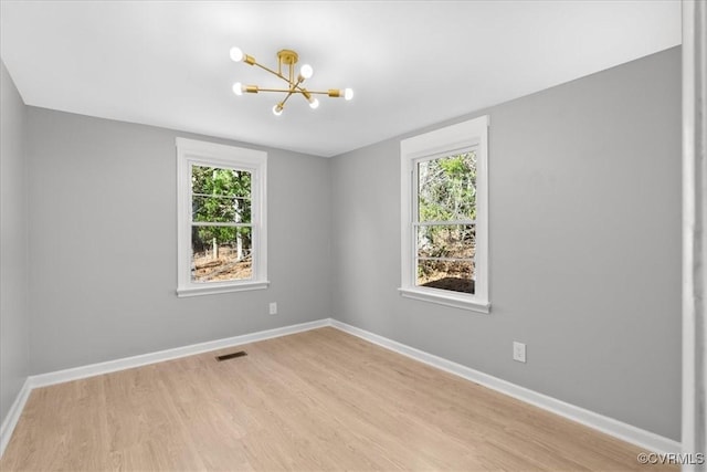 unfurnished room featuring a chandelier and light wood-type flooring