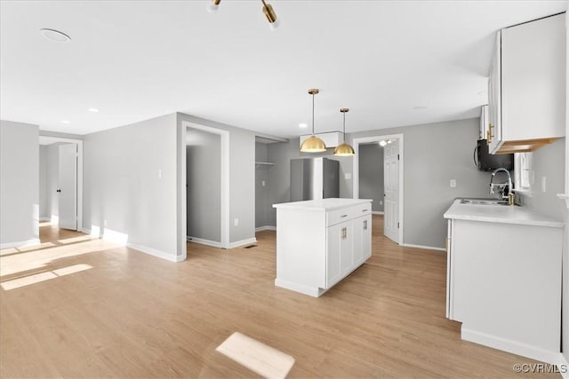 kitchen with sink, white cabinets, a center island, light hardwood / wood-style floors, and stainless steel refrigerator