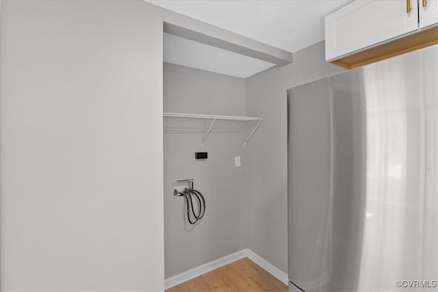 laundry room featuring electric dryer hookup, cabinets, light wood-type flooring, and hookup for a washing machine