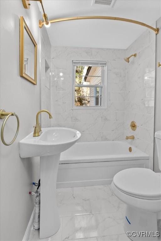 bathroom featuring toilet and tiled shower / bath