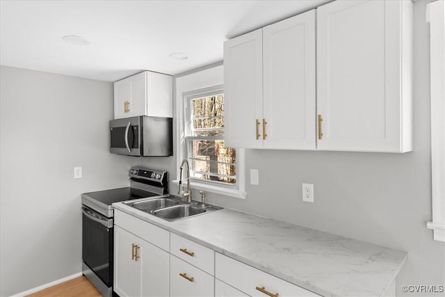 kitchen with white cabinetry, sink, stainless steel appliances, and light wood-type flooring