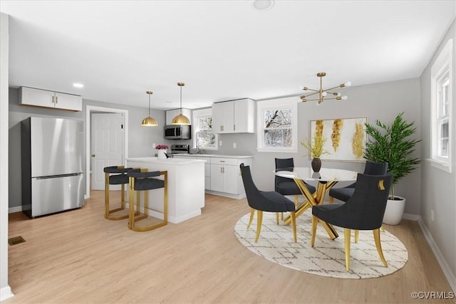 dining room featuring sink, an inviting chandelier, and light hardwood / wood-style flooring