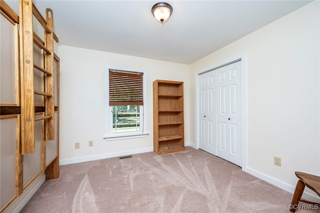 unfurnished bedroom with light carpet and a closet